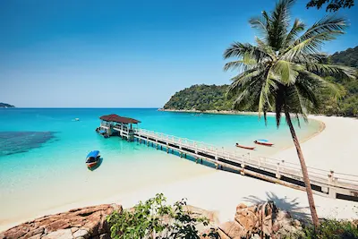 Scenic beach and wooden jetty on Perhentian Island, Malaysia, surrounded by turquoise waters and tropical greenery